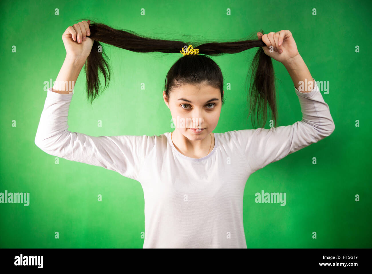 Teengirl im Nachthemd Kämmen Haare am grünen Chroma Key Hintergrund Stockfoto