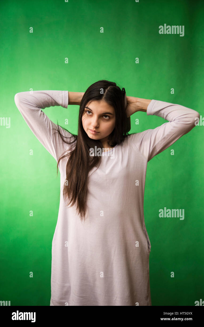 Teengirl im Nachthemd Kämmen Haare am grünen Chroma Key Hintergrund Stockfoto