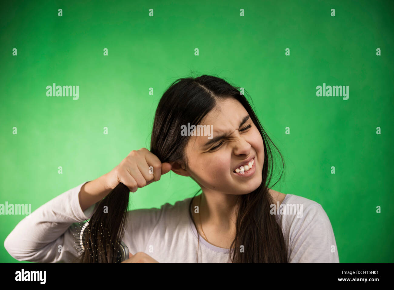 Teengirl im Nachthemd Kämmen Haare am grünen Chroma Key Hintergrund Stockfoto