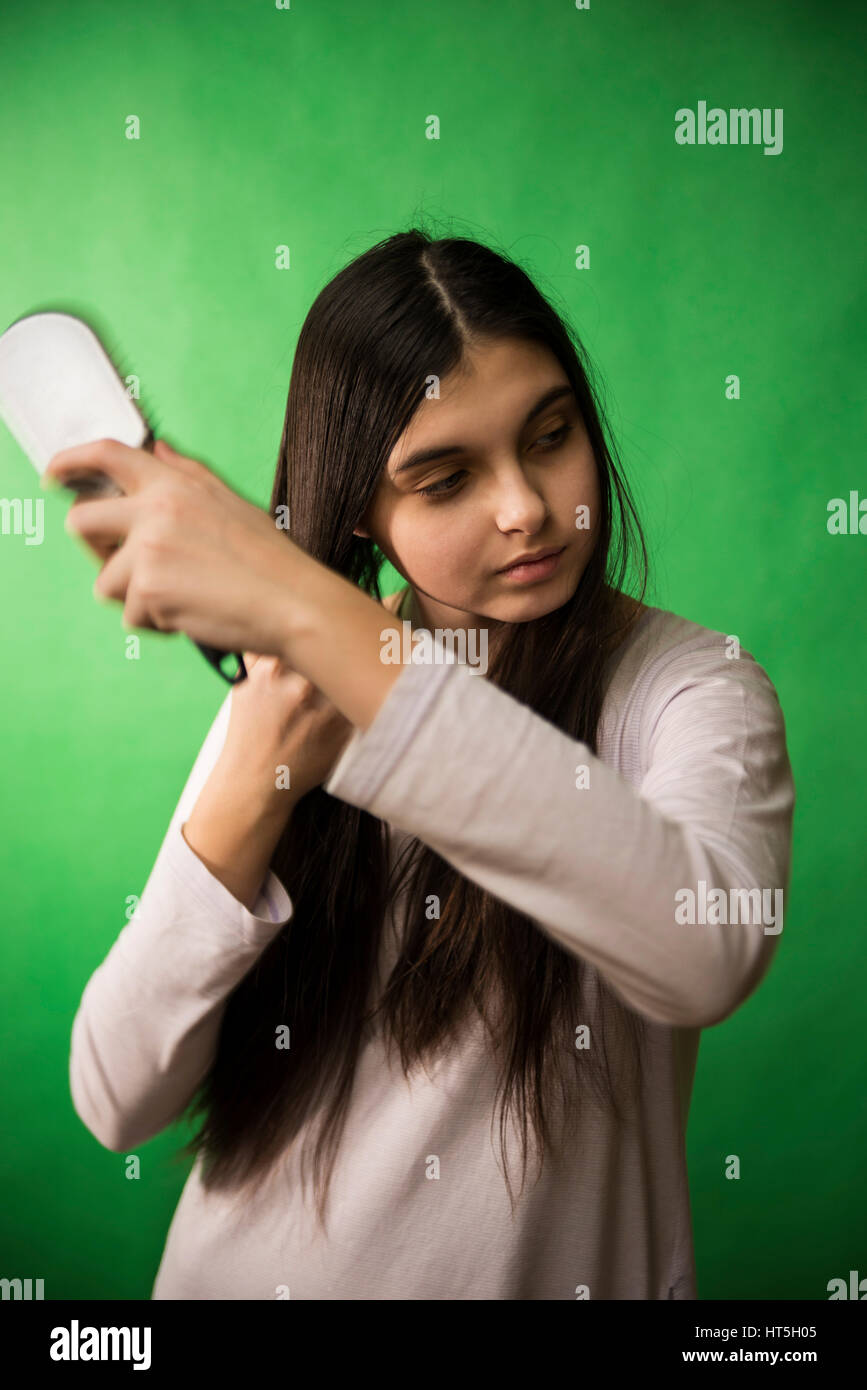 Teengirl im Nachthemd Kämmen Haare am grünen Chroma Key Hintergrund Stockfoto