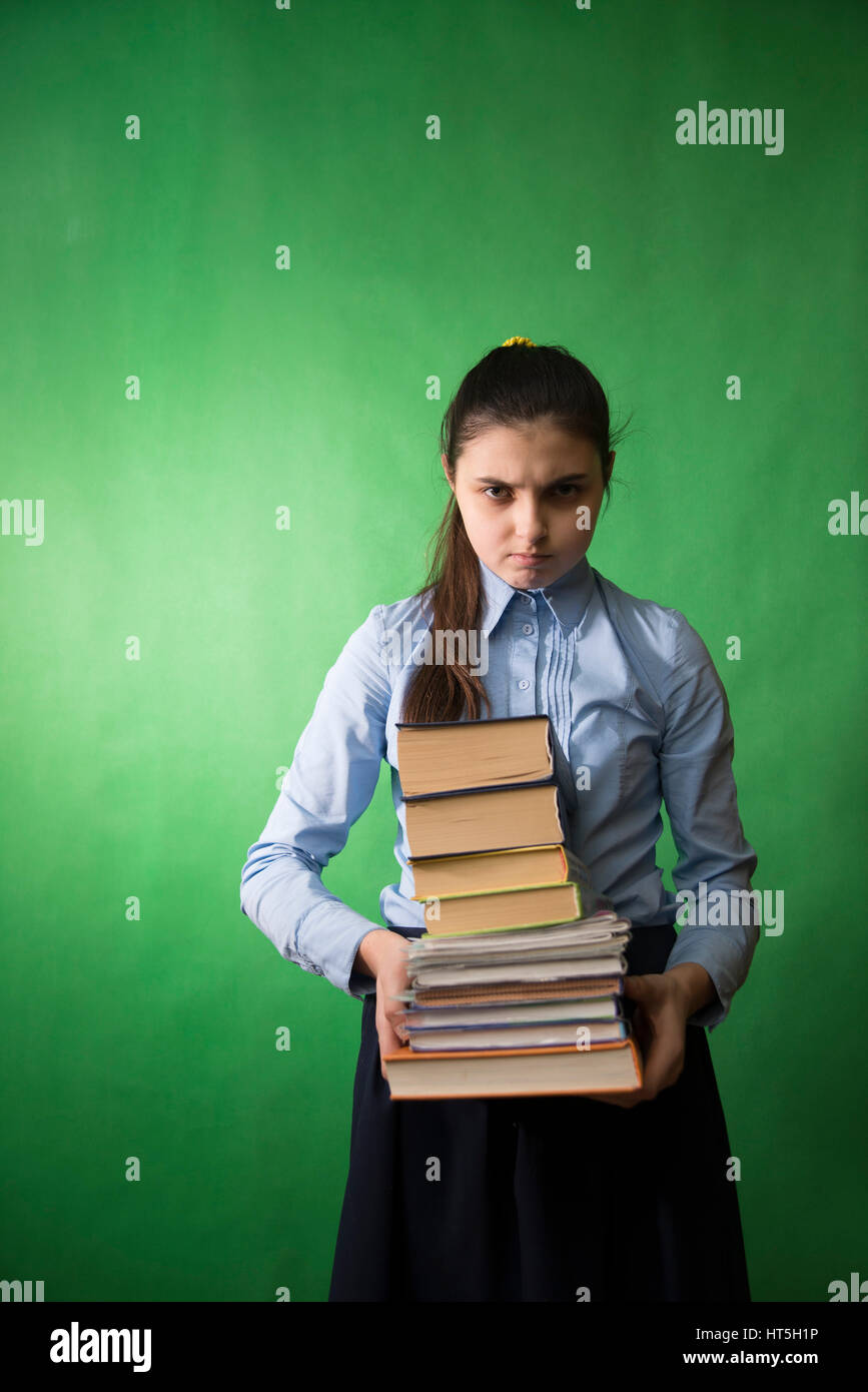 Teen Mädchen mit langen Haaren im blauen Hemd mit einem Stapel Bücher in den Händen Stockfoto