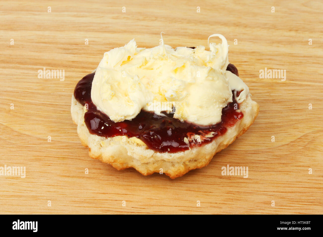 Scones mit Marmelade und Cornish Clotted Cream auf ein Schneidbrett aus Holz Stockfoto