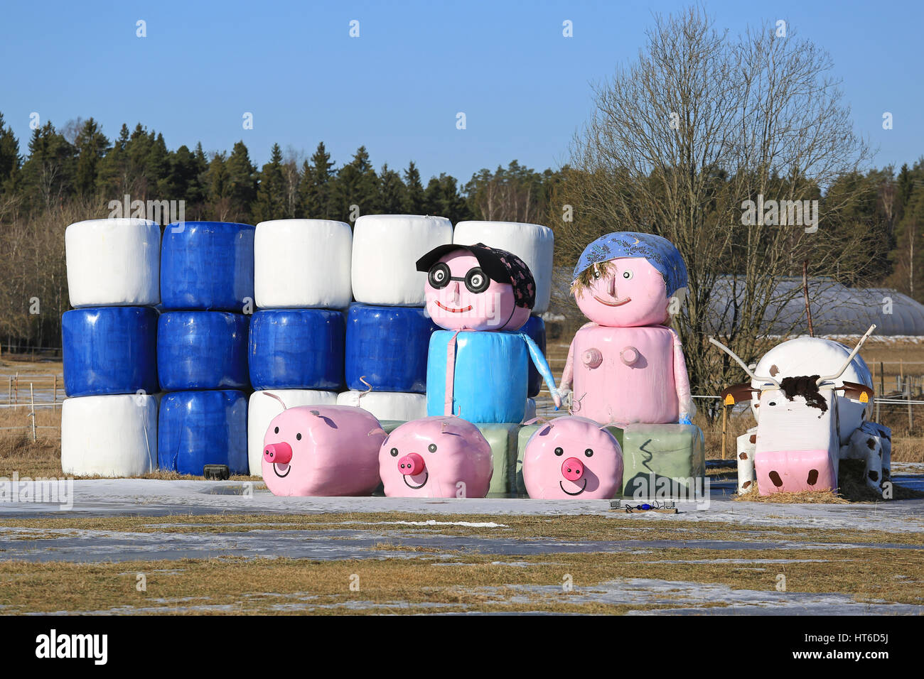 LIETO, Finnland - 5. März 2017: Stilleben auf ein Feld aus der Silageballen von unbekannten mit der Flagge von Finnland, der Landwirt paar und Bauernhof-Tier Stockfoto