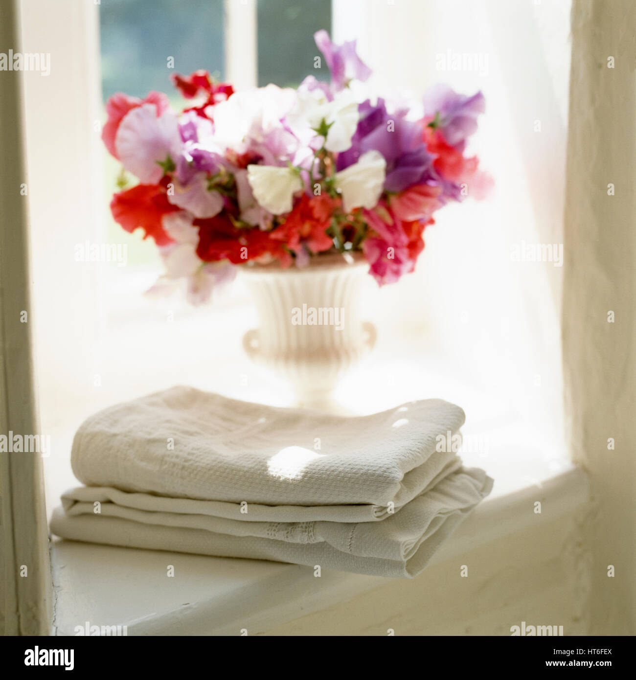 Handtücher und Vase mit Blumen auf der Fensterbank. Stockfoto
