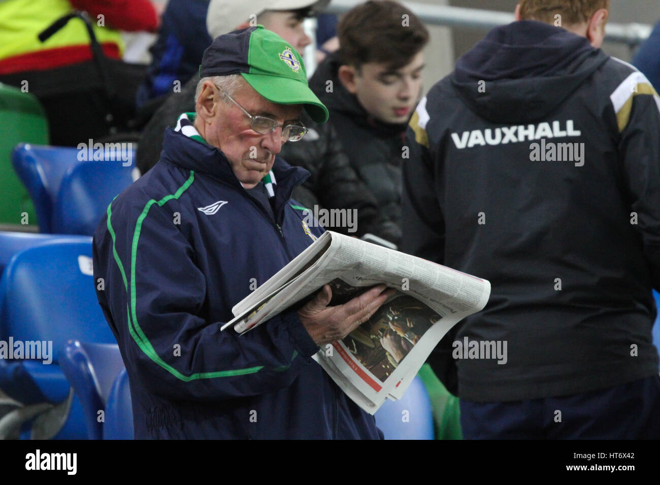 Nationale Fußball-Stadion im Windsor Park, Belfast. 15. November 2016. Internationales Freundschaftsspiel - Nordirland 0 Kroatien 3. Nordirland Unterstützer liest eine Zeitung wie verzögerte Auftakt durch einen Autobahn-Unfall (vergießen LKW Ladung), die Verkehrsprobleme in der Nähe des Bodens verursacht. Das Spiel startete 15 Minuten später als geplant. Stockfoto