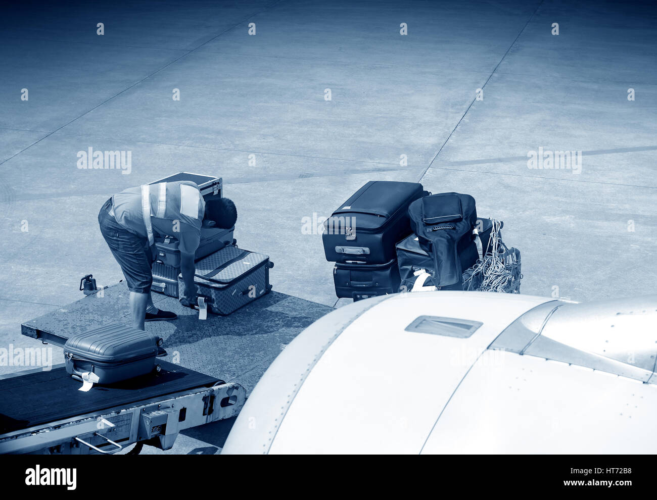 Ein Mann wird Gepäck auf Flugzeug geladen. Stockfoto
