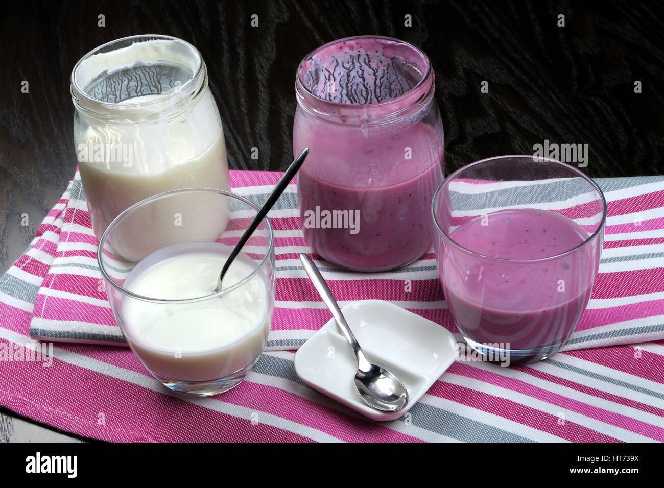 Hausgemachte Bio fettarmer schlicht und Heidelbeer Joghurt in einem klaren Glas (und Glas) mit einem Teelöffel auf bunte Küchentücher Stockfoto