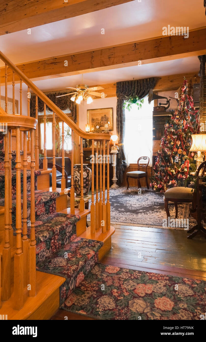 Elegante Holztreppe und Wohnzimmer mit Weihnachtsbaum in einem 1904 Altes Haus im viktorianischen Stil eingerichtet. Stockfoto