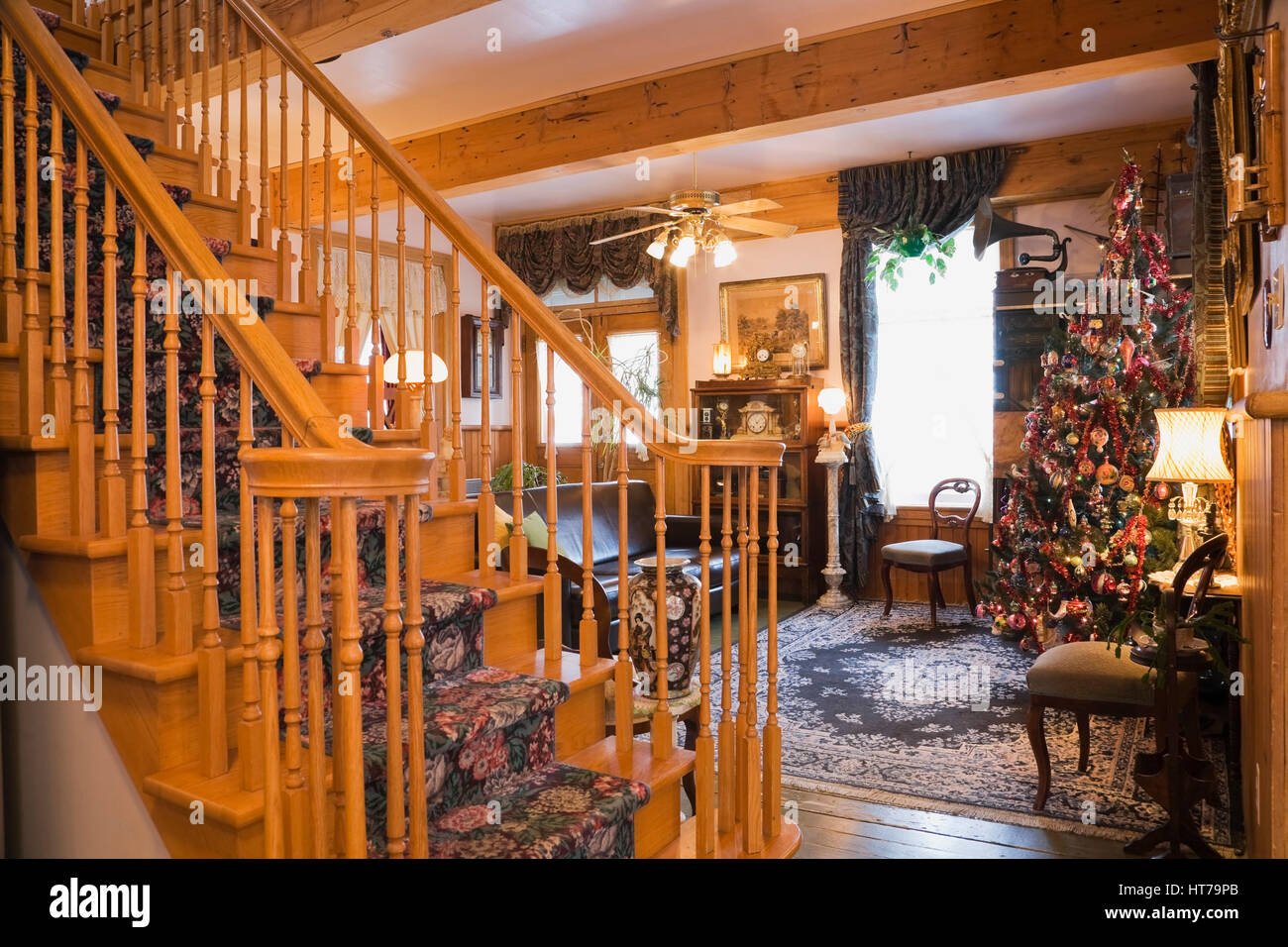 Elegante Holztreppe und Wohnzimmer mit Weihnachtsbaum in einem 1904 Altes Haus im viktorianischen Stil eingerichtet. Stockfoto