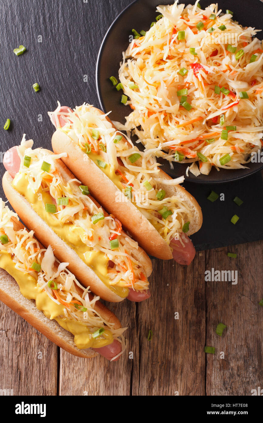 Leckere Hot Dog mit Bratwurst, Sauerkraut und Senf close-up auf dem Tisch. Vertikale Ansicht von oben Stockfoto