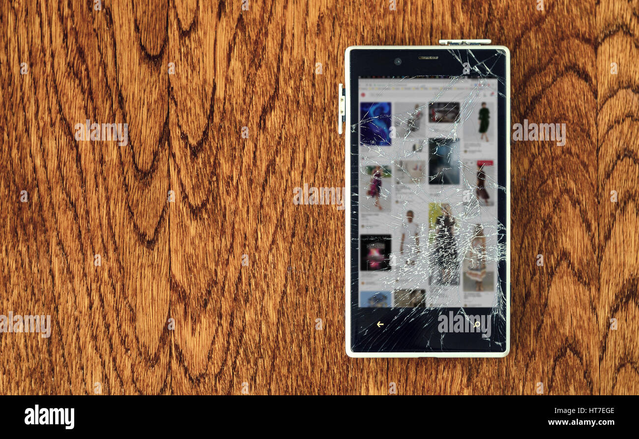 White Smartphone mit gebrochenen Bildschirm auf Holztisch. Verlust der Verbindung Konzept Stockfoto