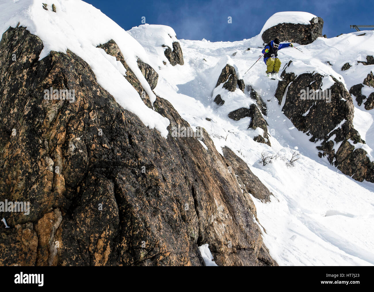 Ein Skifahrer einen Sprung von einer kleinen Steilküste und Fänge Luft an einem sonnigen Tag Skifahren am Cerro Catedral In Argentinien Stockfoto