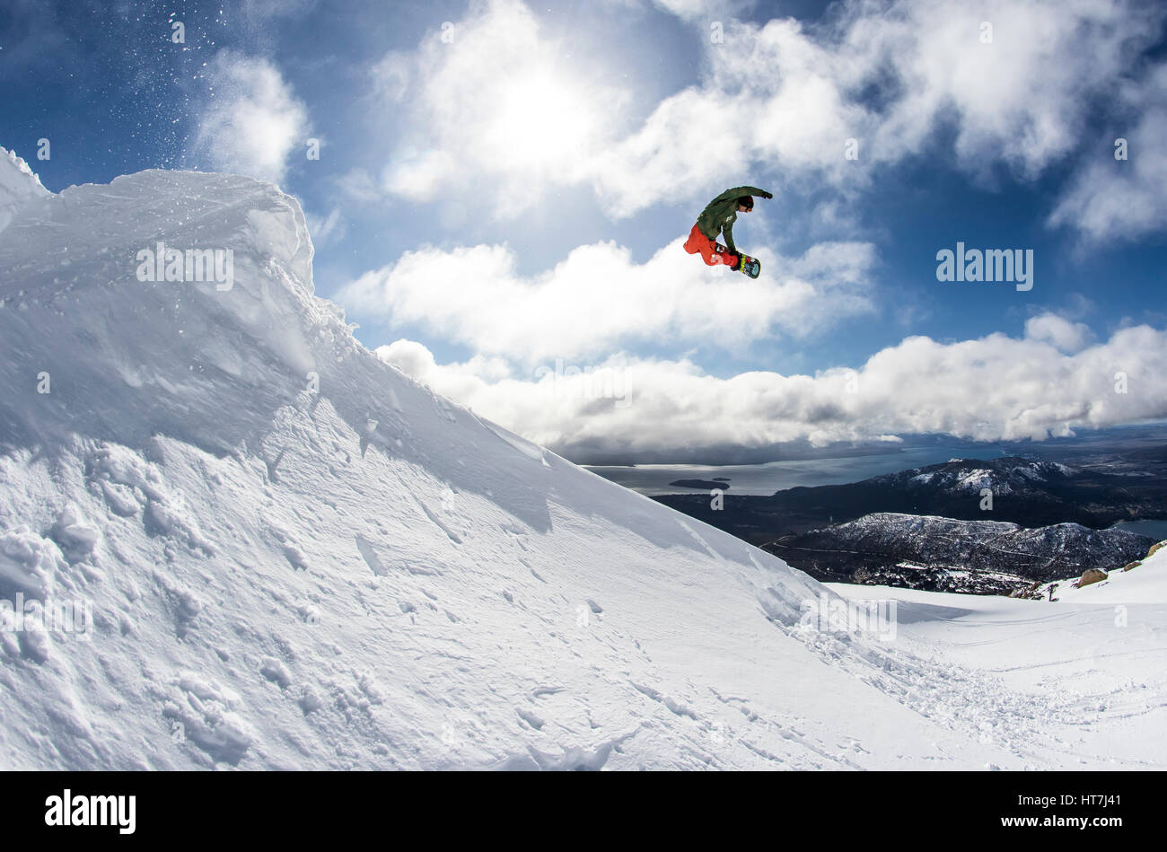 Ein Snowboarder trifft einen Backcountry-Sprung und macht eine Methode greifen an einem sonnigen Tag im Backcountry um Cerro Catedral In Argentinien Stockfoto