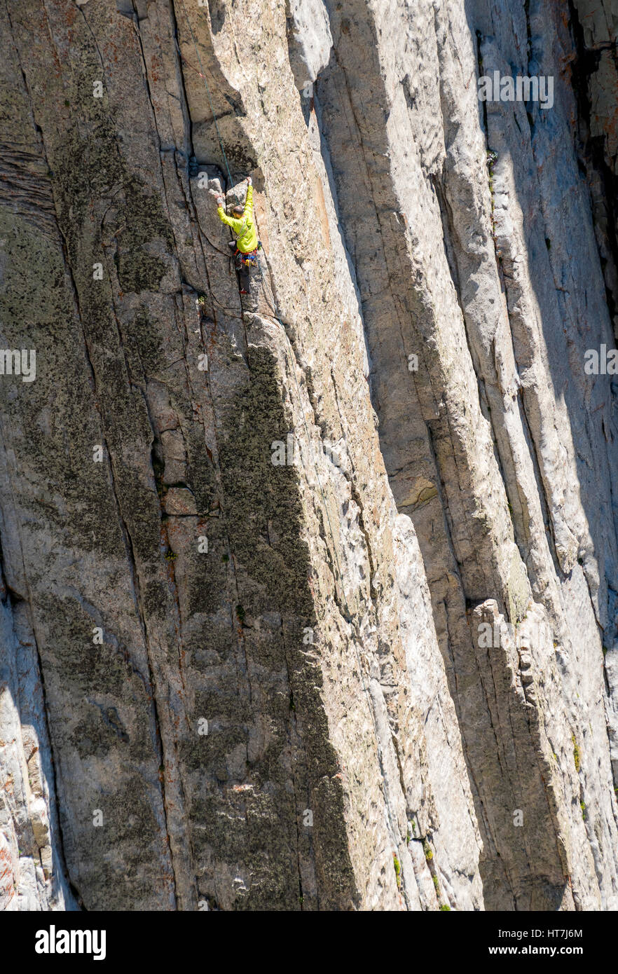 Ein Mann nach seinen Freunden auf einem Felsen klettern auf Utahs einsame Spitze arbeitet seinen Weg durch eine knifflige Bewegung Stockfoto