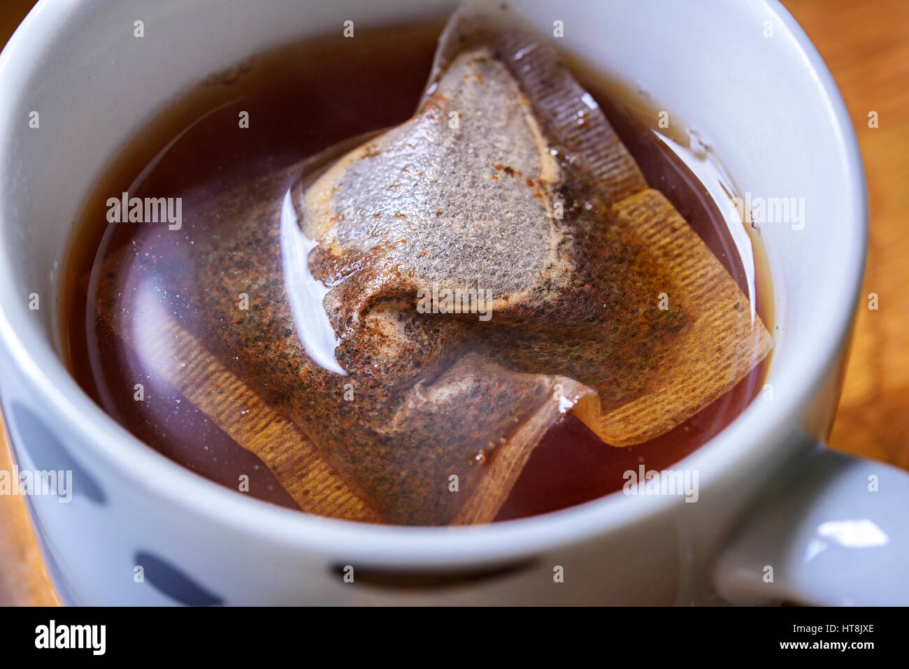 Tasse traditionelles englisches Frühstückstee gemacht. Bild zeigt Teebeutel in eine Tasse kochendes Wasser hineingießen. Schwimmt auf der Oberfläche Stockfoto