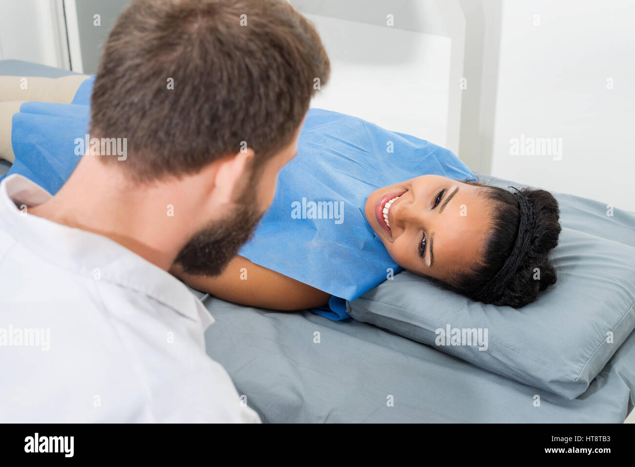 Lächelnd, weibliche Patienten betrachten männlichen Arzt untersucht sie in Klinik Stockfoto