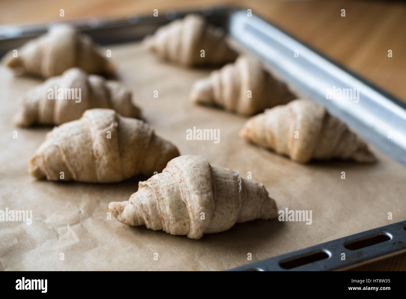 Roh nicht gebackene Vollkorn Croissants auf Backblech mit Backpapier Stockfoto