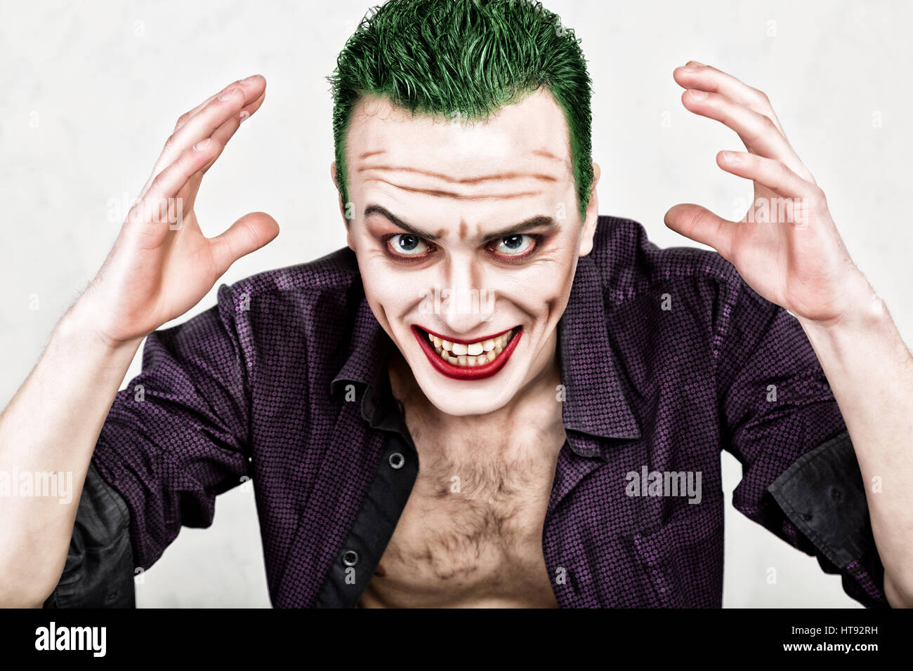 Kerl mit verrückten Joker Gesicht, grüne Haare und idiotische Smike. Karneval Kostüm. Stockfoto