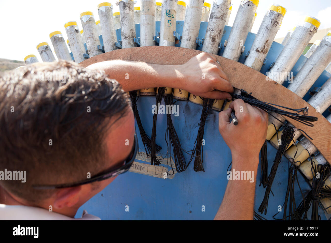 Eine maltesische Pyrtechnician Zahlen Rohre gefüllt mit Feuerwerk beim Aufbau einer professionellen pyrotechnischen Show in Aufmachungen für eine katholische fest. Stockfoto