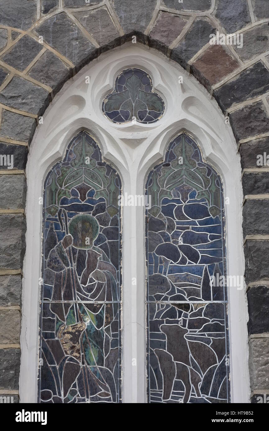 Gewölbte Glasfenster mit weißen Holzrahmen auf Stein Kirchenmauer. Stockfoto
