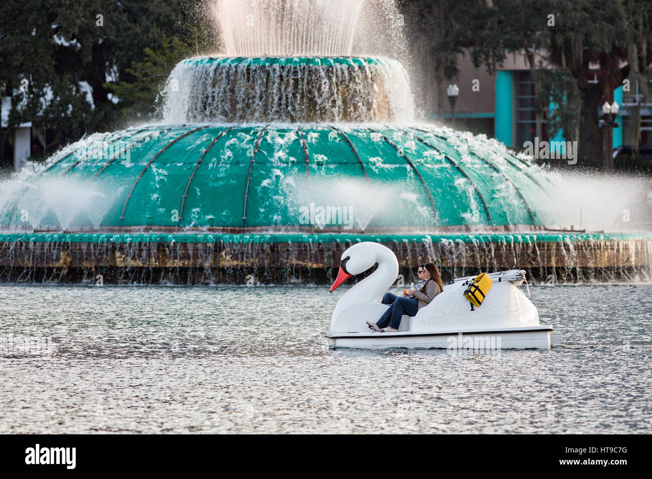 Touristen paddeln Swan Boote rund um Lake Eola Park vorbei Linton E. Allen Memorial Fountain in Orlando, Florida. Lake Eola Park ist gelegen im Herzen von Downtown Orlando und Heimat der Walt-Disney-Amphitheater. Stockfoto