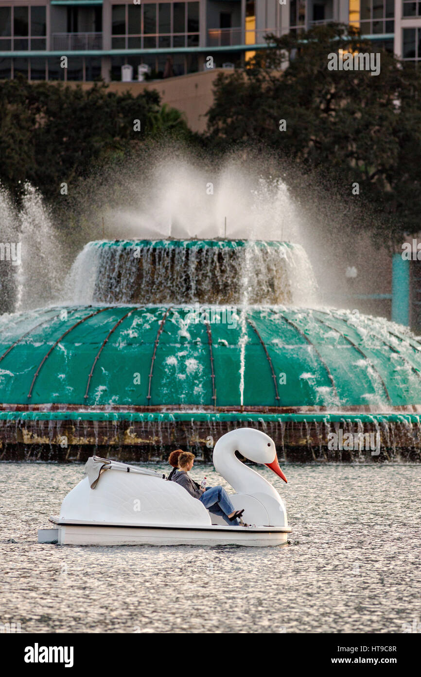Touristen paddeln Swan Boote rund um Lake Eola Park vorbei Linton E. Allen Memorial Fountain in Orlando, Florida. Lake Eola Park ist gelegen im Herzen von Downtown Orlando und Heimat der Walt-Disney-Amphitheater. Stockfoto