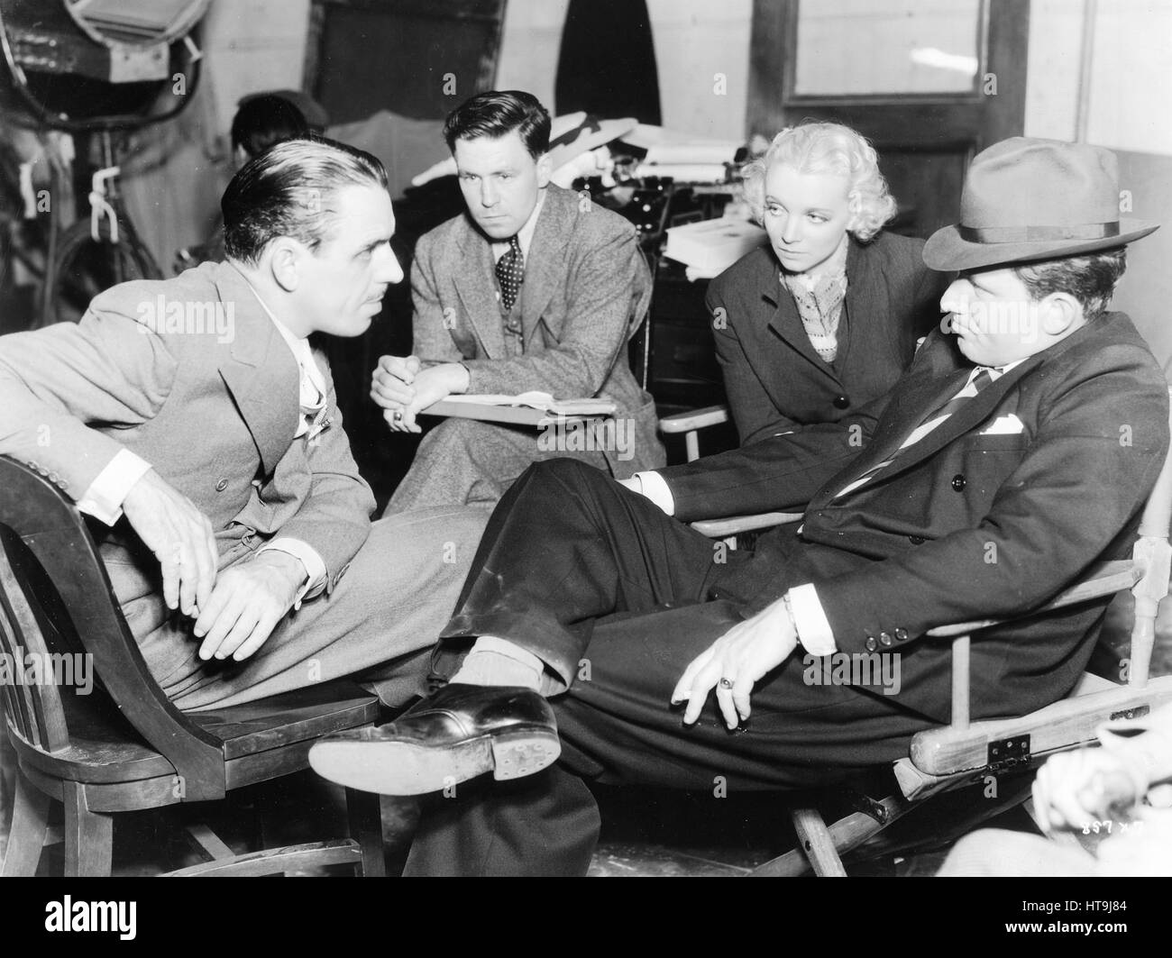 "Dies ist der Weg, die Studio-Konferenzen... Oder einige von ihnen, mindestens. Regisseur Tim Whelan und Scenarist Ed Higgins sprechen über Szenen des"The Murder" mit Spencer Tracy, Stern, und Virginia Bruce, seine Hauptdarstellerin nur bevor Szenen gedreht werden. Das Bild ist von Harry Rapf für Metro-Goldwyn-Mayer produziert. " Stockfoto