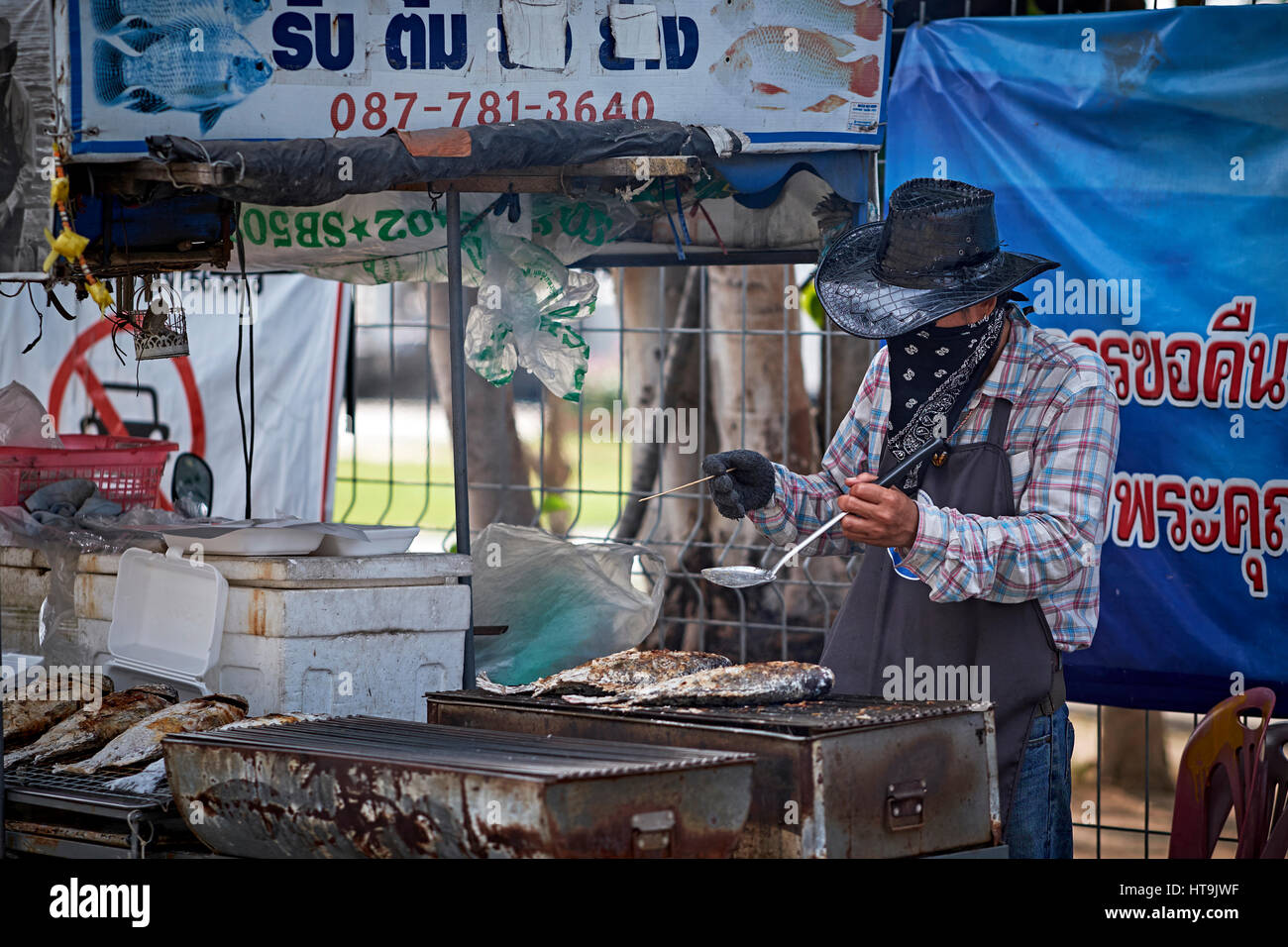 Thailand Street Food Verkäufer Kochen in seinem Fischstand und trägt eine Gesichtsmaske. Thailand Südostasien Stockfoto