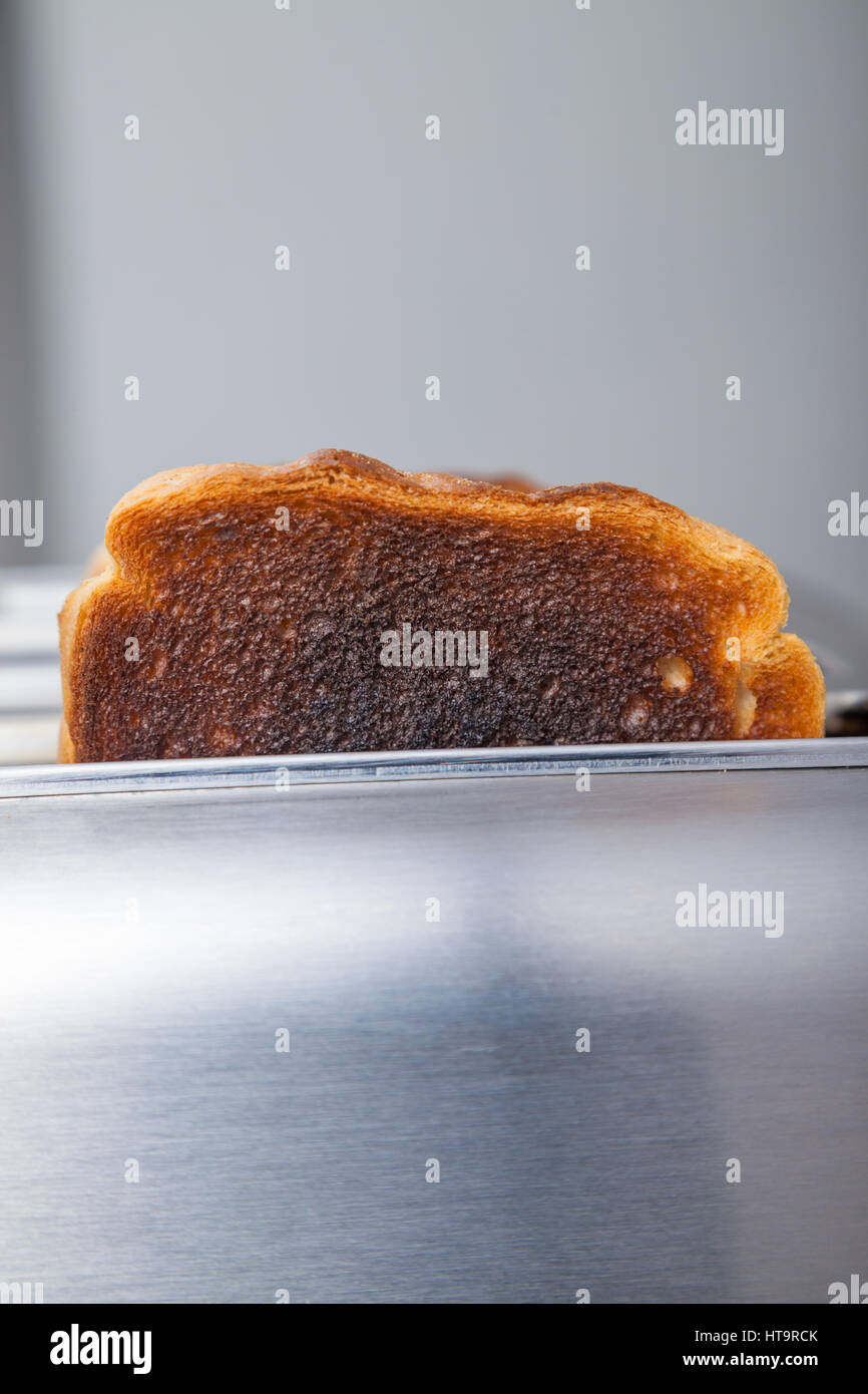 Zwei Scheiben von verbranntem Toast in einem Metall Toaster. Stockfoto