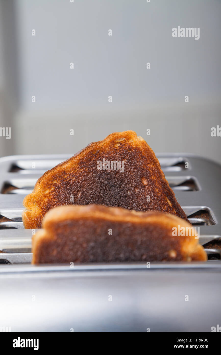 Zwei Scheiben von verbranntem Toast in einem Metall Toaster. Stockfoto