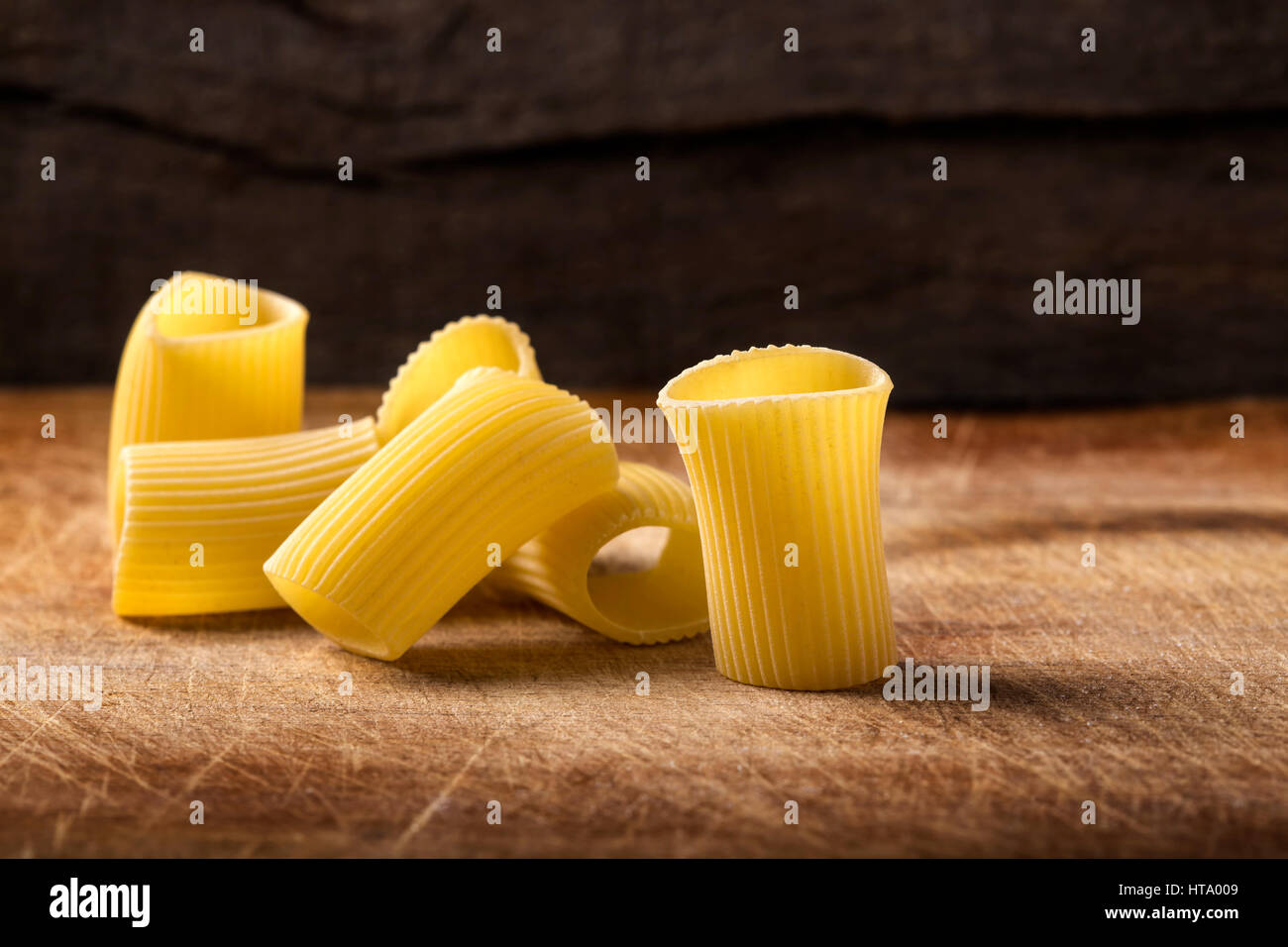Rohe italienische Makkaroni Nudeln und einige auf hölzernen Hintergrund Stockfoto