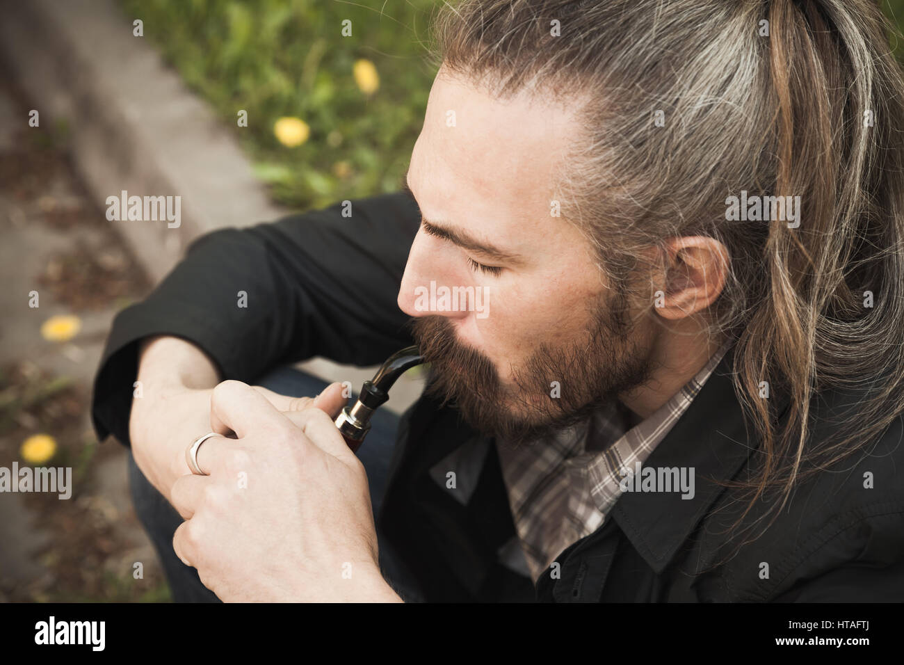 Junge asiatische bärtiger Mann rauchen Pfeife im Sommerpark, Nahaufnahme portrait Stockfoto