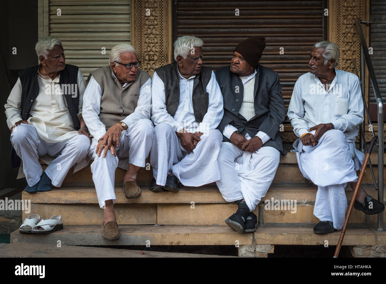 Eine Versammlung gleichgesinnter in Jaisalmer, Indien: mittleren Alters und ältere Männer im Gespräch mit einander auf Straßenseite Schritte. Stockfoto