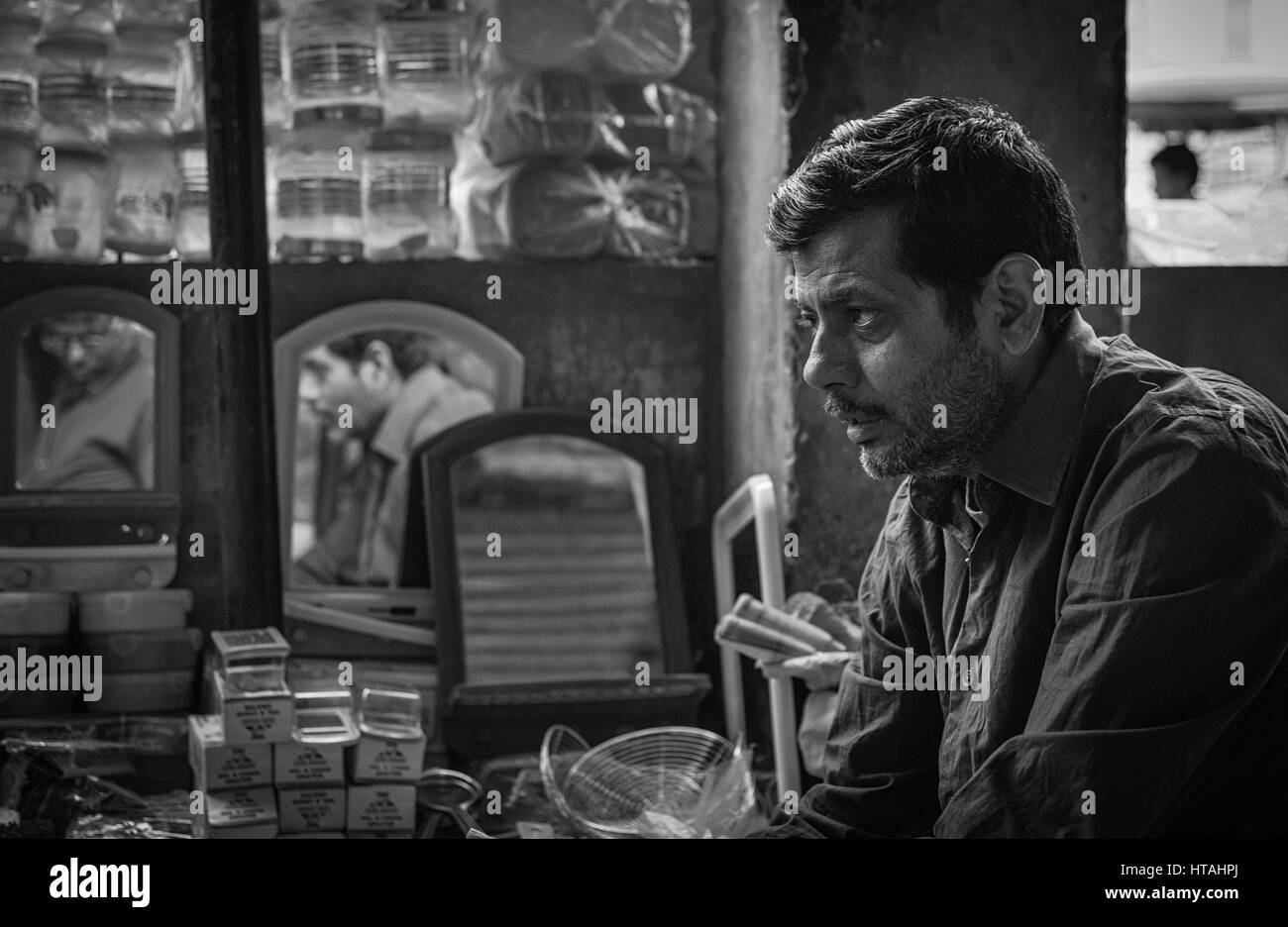 Ein Mann gedankenverloren sitzend in seinem Geschäft in Jaipur, Indien. Stockfoto