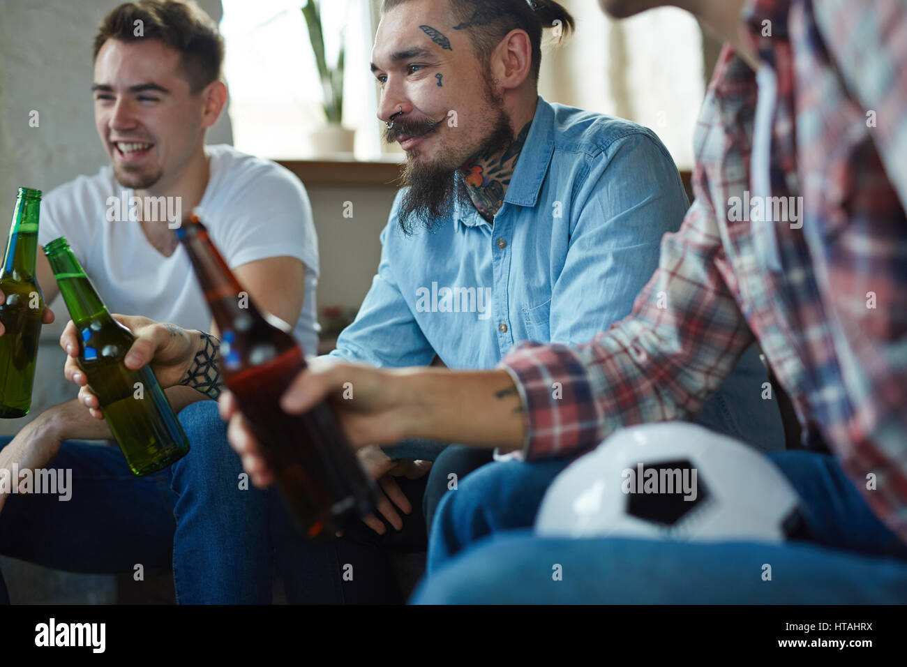 Mann mit Bart und Tattoos halten Flasche Bier beim Fußball gucken tv Sendung Stockfoto