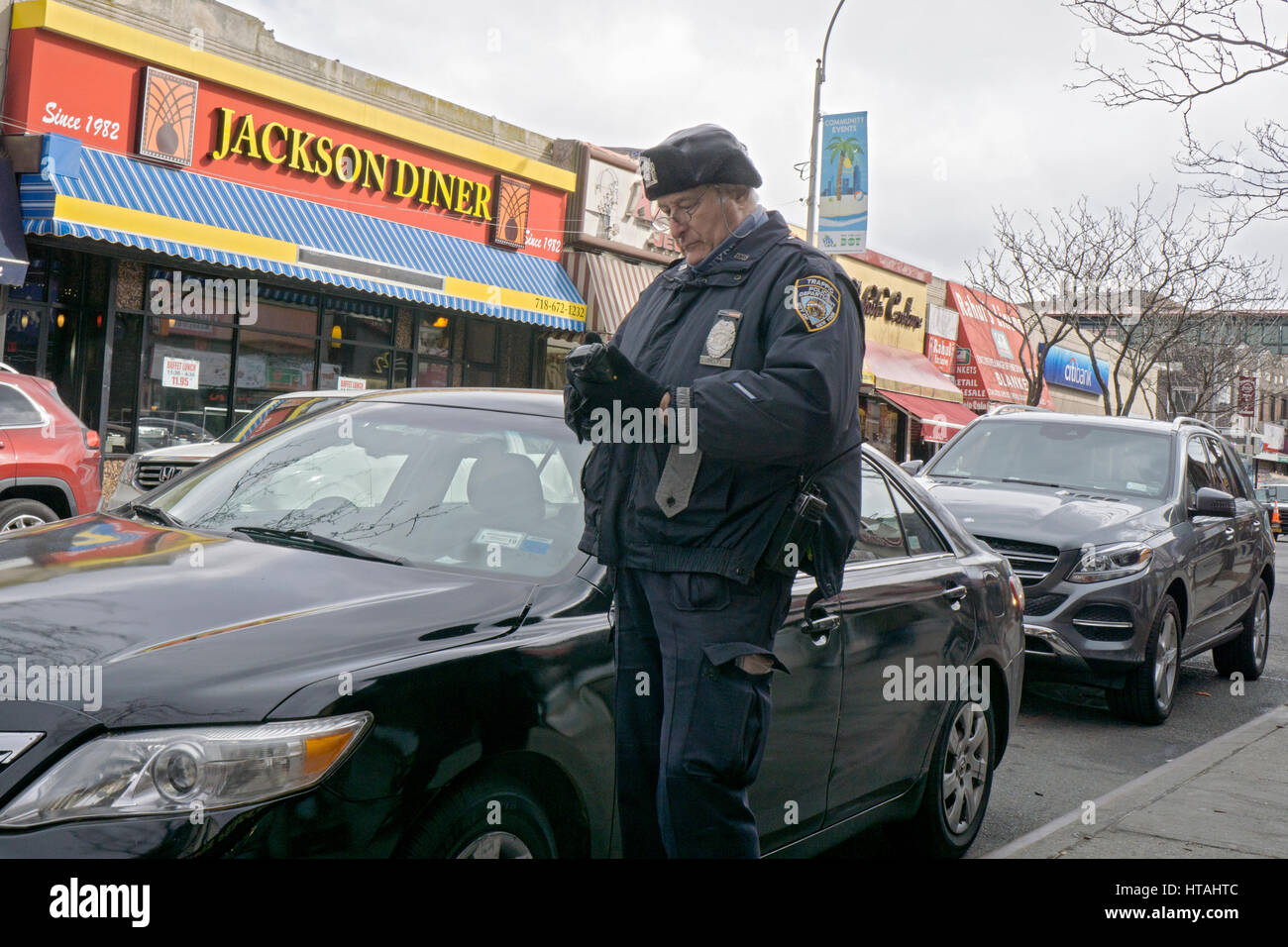 Ein New York City Verkehrspolizist schreiben eine Vorladung für ein Auto mit einer Verletzung der Parkplatz an der 74th Street in Jackson Heights, Queens, New York City. Stockfoto