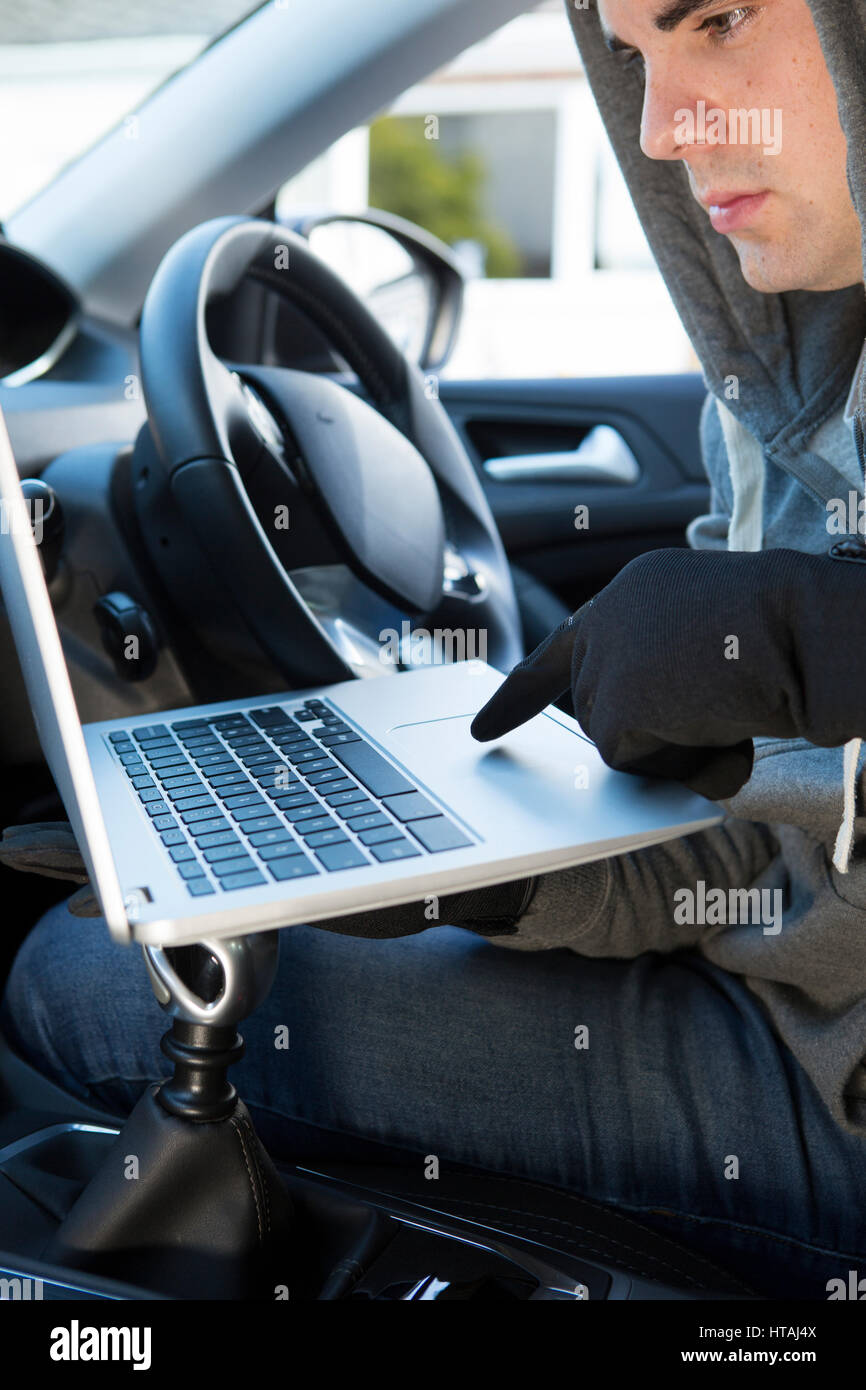 Dieb mit Laptop, Hack in Auto-Sicherheits-Software Stockfoto