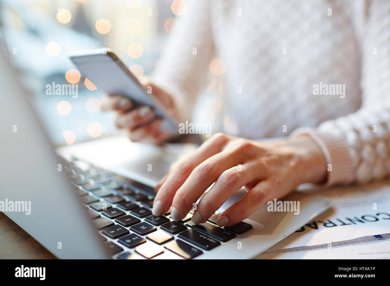 Nahaufnahme von unkenntlich beschäftigte Frau Multitasking: Smartphone in der hand halten und schreiben Nachricht während der Arbeit mit Laptop und Dokumentation im Café Stockfoto