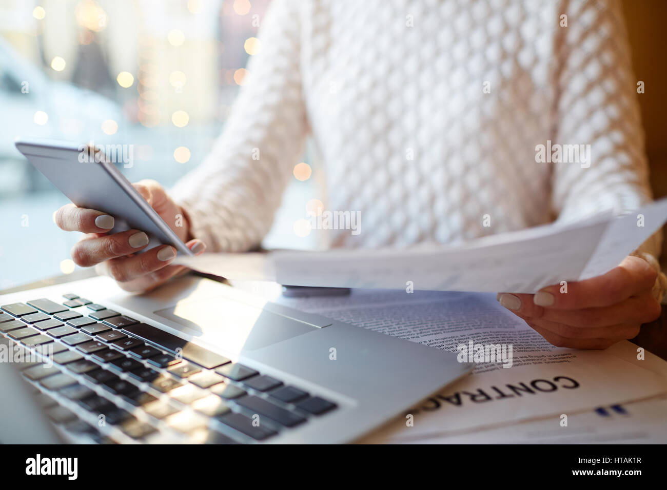 Nahaufnahme von unkenntlich beschäftigte Frau Multitasking: Dokumente in der hand halten, Smartphone Nachricht eintippen und Überprüfung von Verträgen und Statistiken Whil Stockfoto