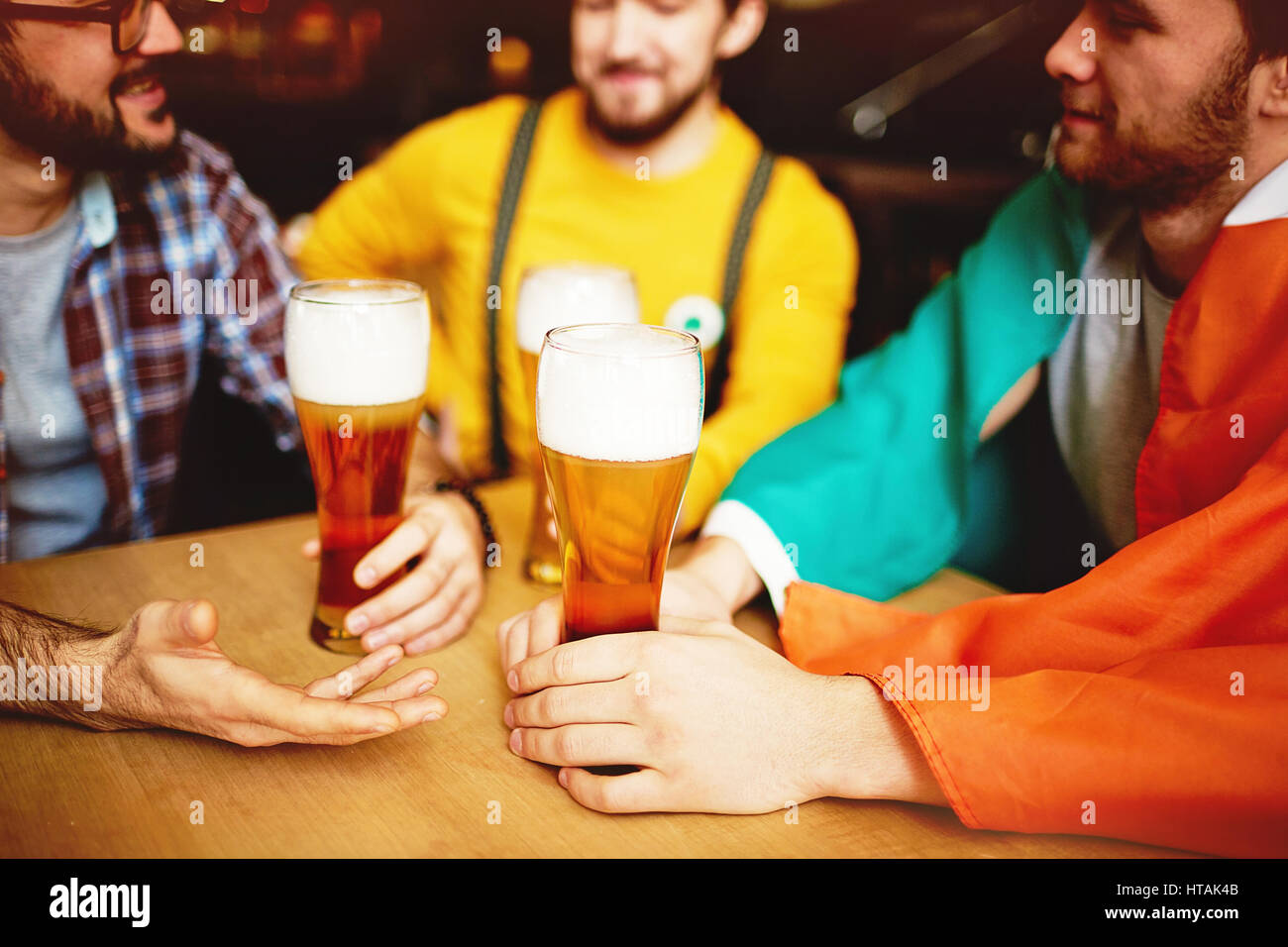 Drei Männer treffen im Irish Pub genießen Sie Unterhaltung und Handwerk Bier, konzentrieren sich auf hohe Gläser auf Tisch Stockfoto