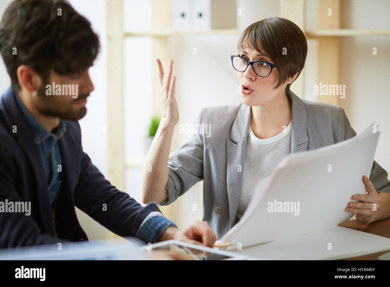 Porträt von zwei erfolgreiche Geschäftsleute, die Kommunikation im Büro, energische Frau gestikulieren aktiv erläutert und Arbeitspläne und Dokumentation d Stockfoto