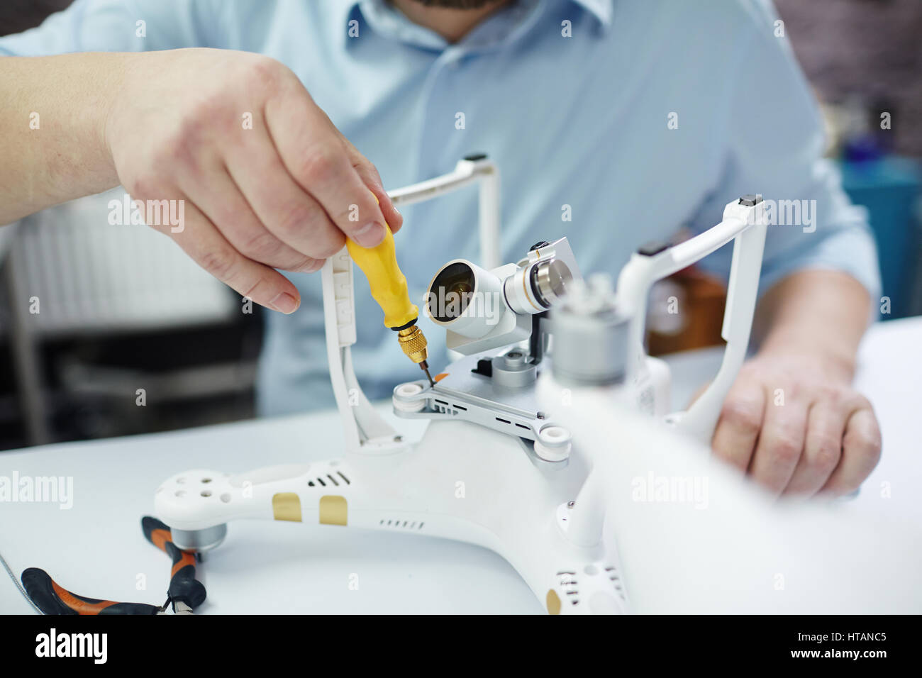 Closeup Aufnahme unkenntlich Mann arbeitet auf Montage neue Spy-System mit Quadrocopter Drohne auf Tisch mit verschiedenen Werkzeugen in moderne Werkstatt Stockfoto