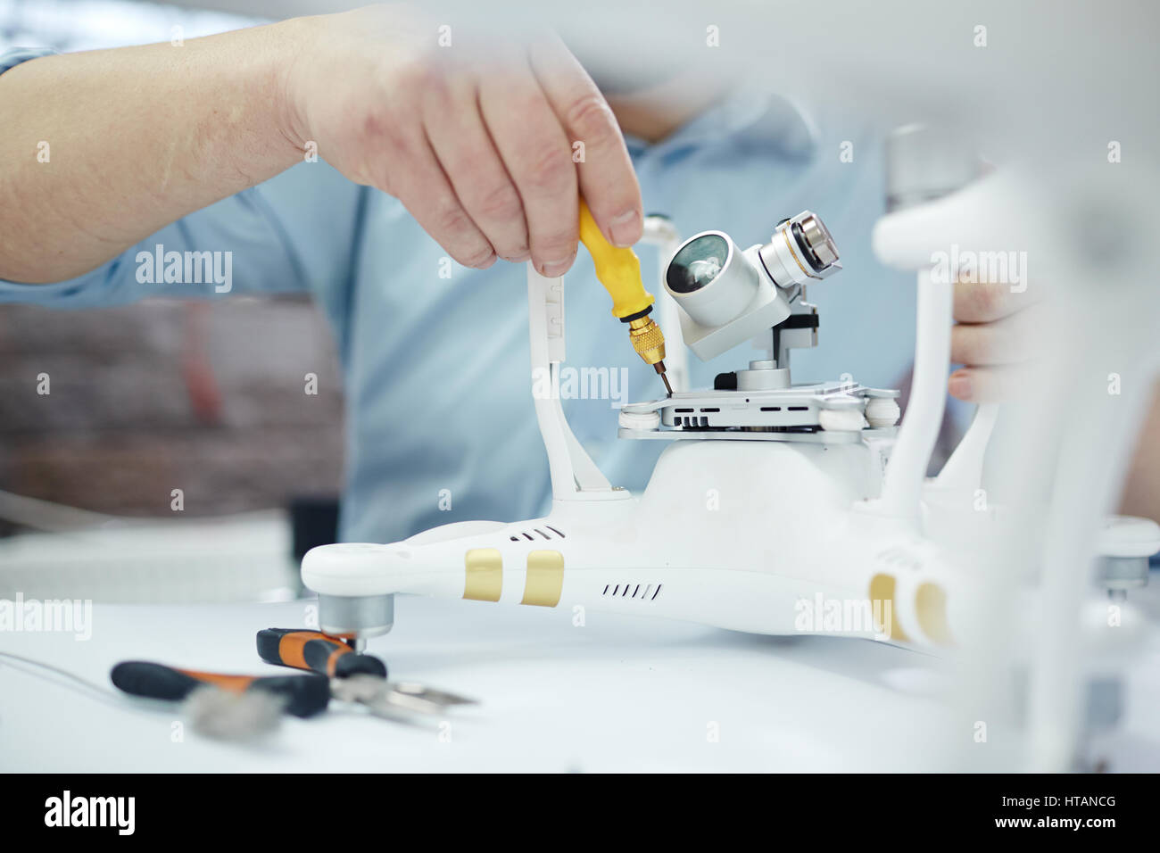 Closeup Aufnahme von männlichen Händen Montage neue Überwachungssystem mit Quadrocopter Drohne auf Tisch mit verschiedenen Werkzeugen in moderne Werkstatt Stockfoto