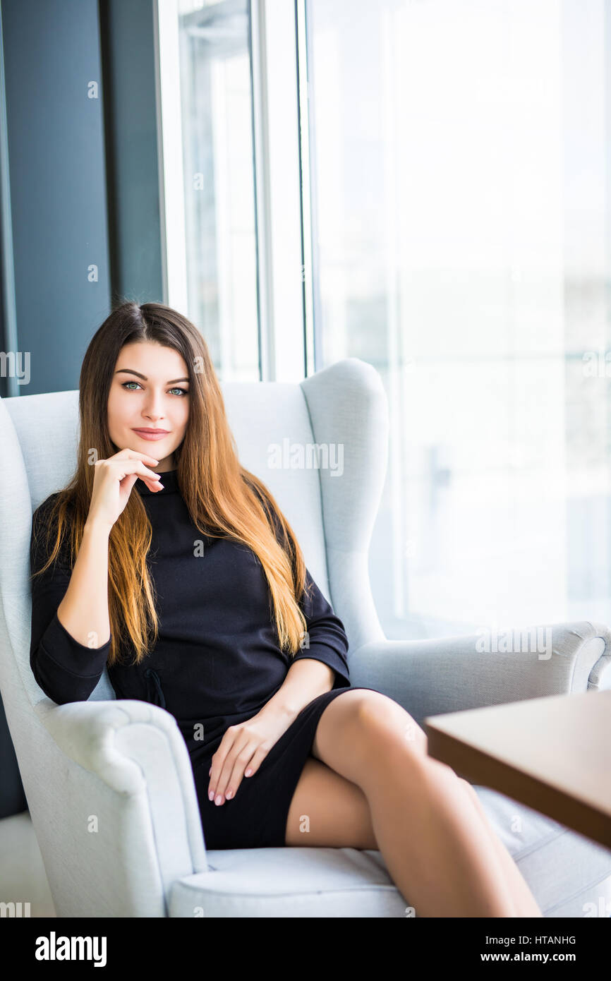 Attraktive junge Frau auf einem Stuhl in einem Café sitzend Stockfoto