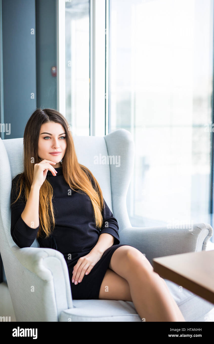 Attraktive junge Frau auf einem Stuhl in einem Café sitzend Stockfoto