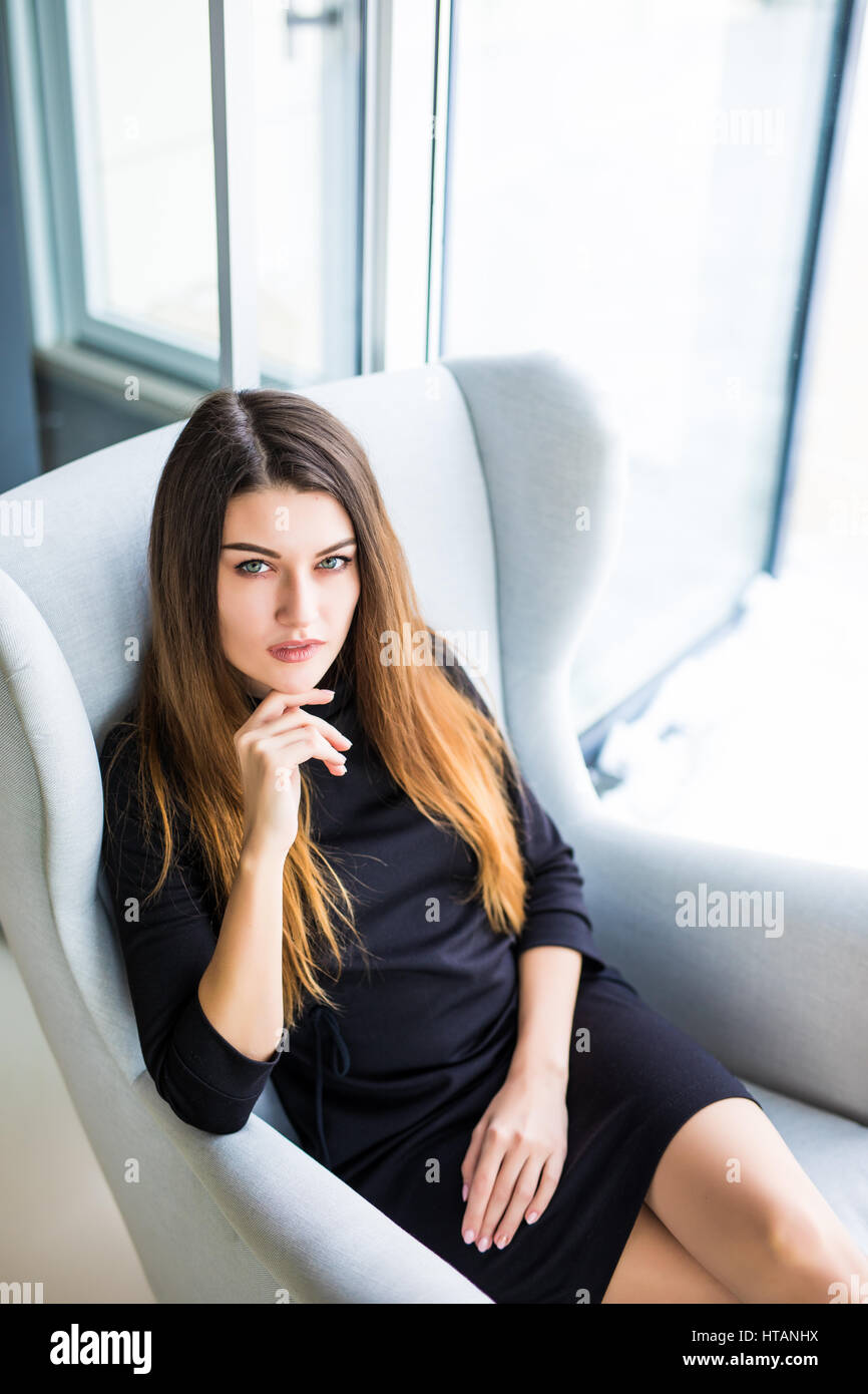 Attraktive junge Frau auf einem Stuhl in einem Café sitzend Stockfoto