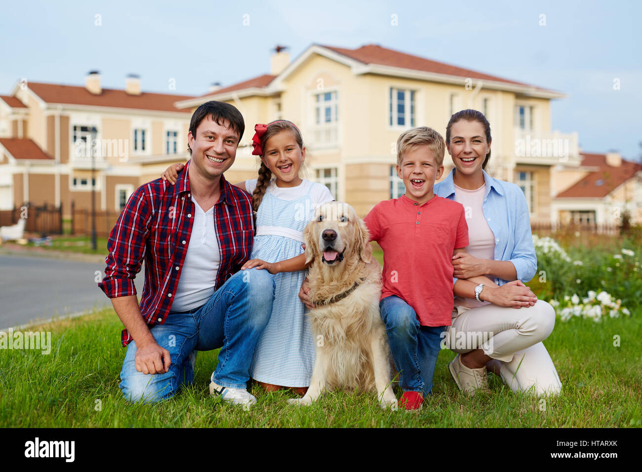 Porträt des erfolgreichen glückliche Familie mit zwei Kindern, jungen und Mädchen und ihre golden Retriever Hund sitzen zusammen auf grünem Rasen gegen backg Stockfoto