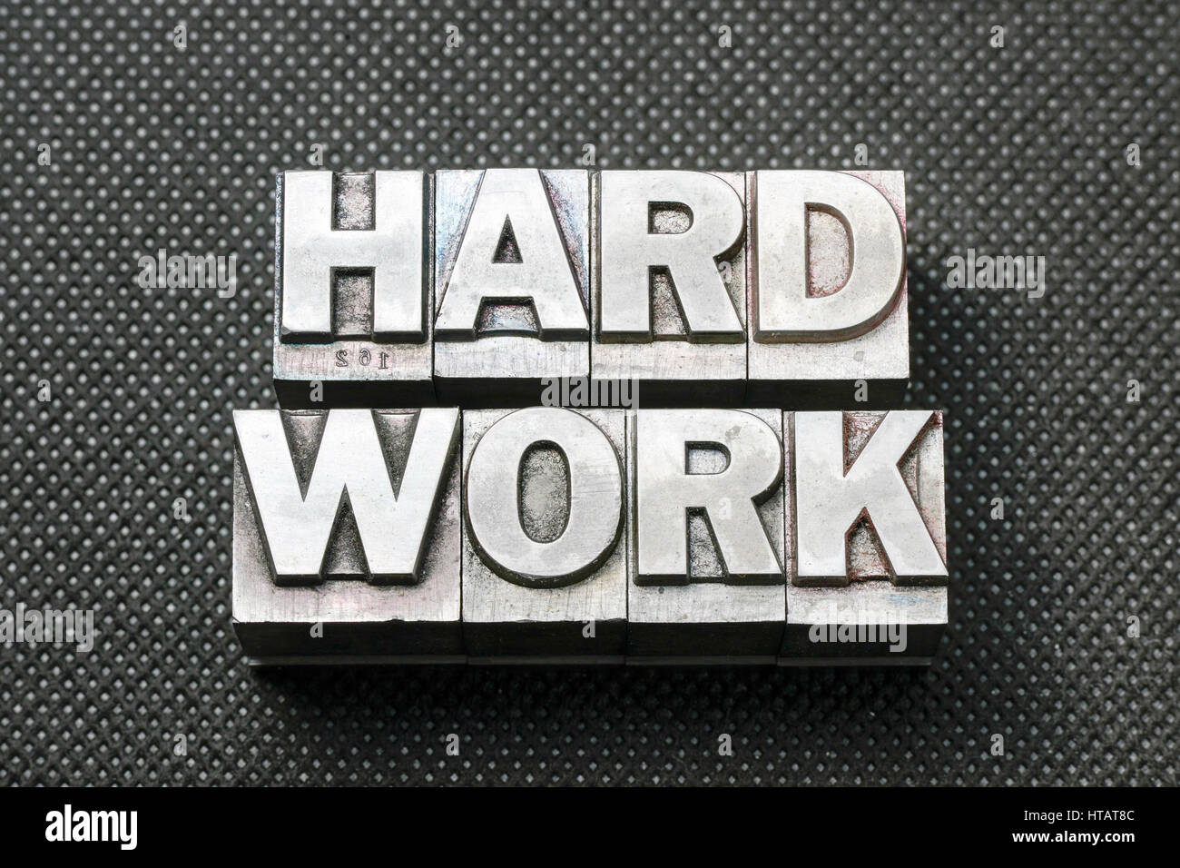 harte Arbeit-Satz aus metallischen Buchdruck Blöcke auf schwarze gelochte Oberfläche hergestellt Stockfoto