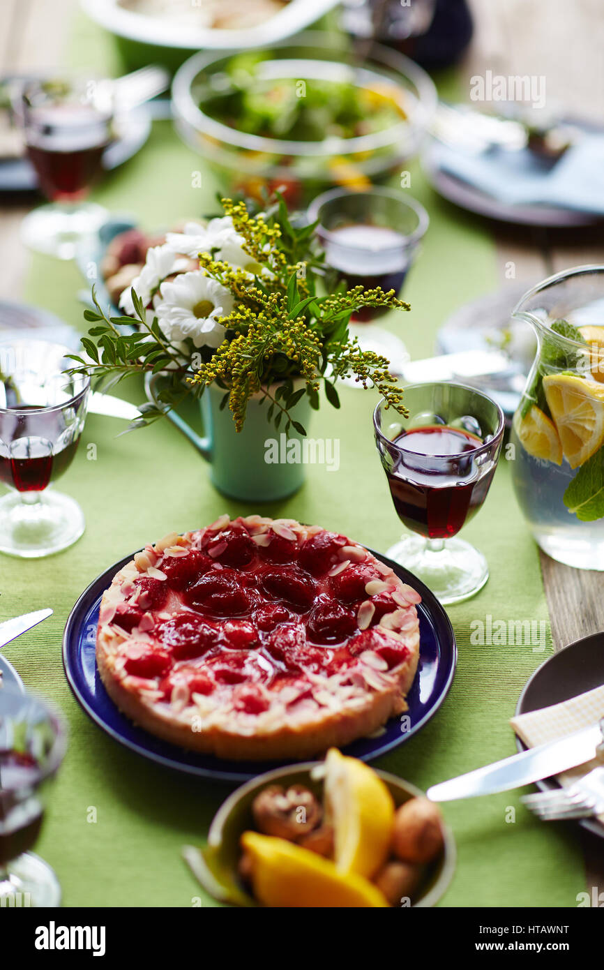 Leckere Dessert frische Blumen, hausgemachtes Getränk und Rotwein auf festlich gedeckten Tisch Stockfoto