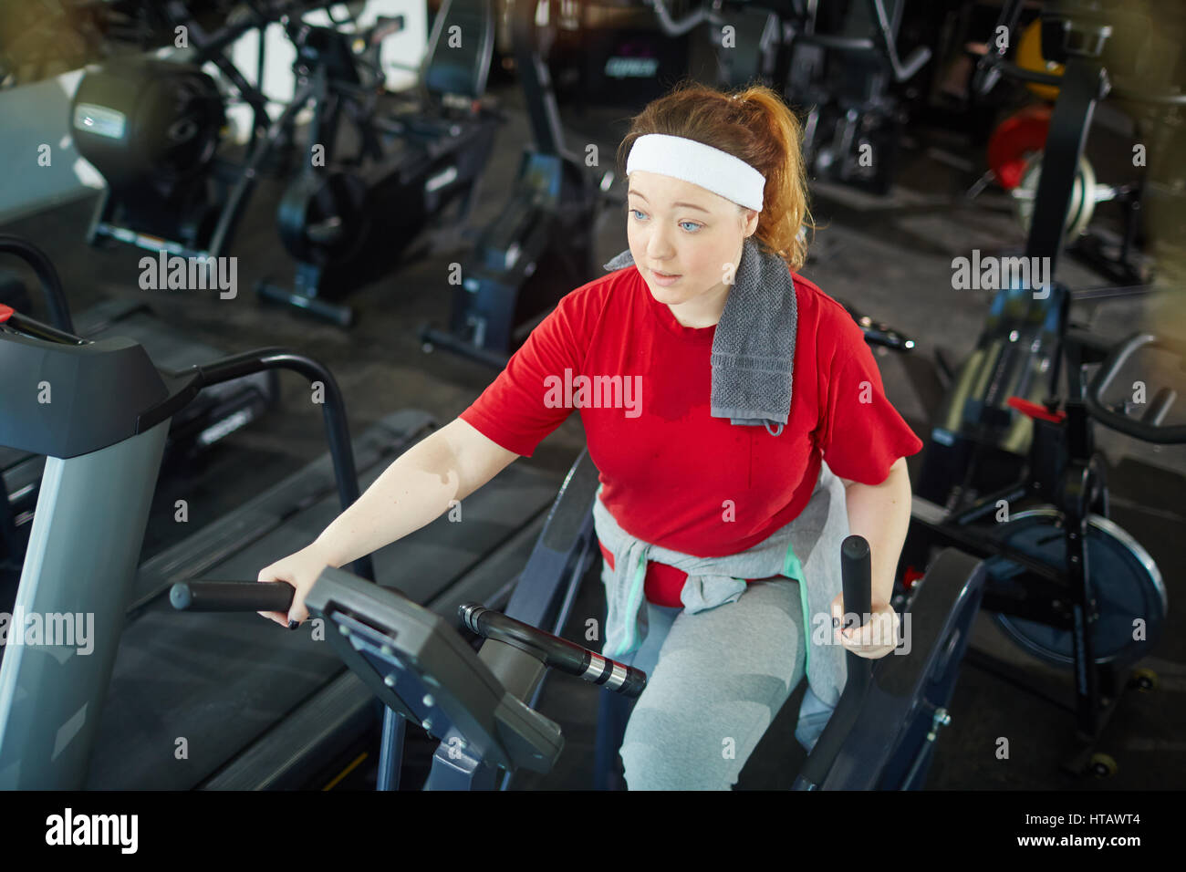 Hohen Winkel Porträt von niedlichen übergewichtige Frau mit roten Haaren  Training mit Crosstrainer im Fitness-Studio Stockfotografie - Alamy